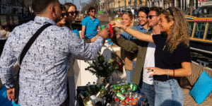 Group of friends enjoying drinks on a sunny Kinboat canal cruise in Amsterdam