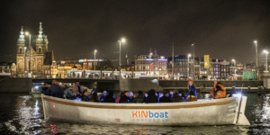 KINboat evening canal cruise passing Amsterdam’s illuminated skyline near Central Station, perfect after visiting the Amsterdam Dungeon