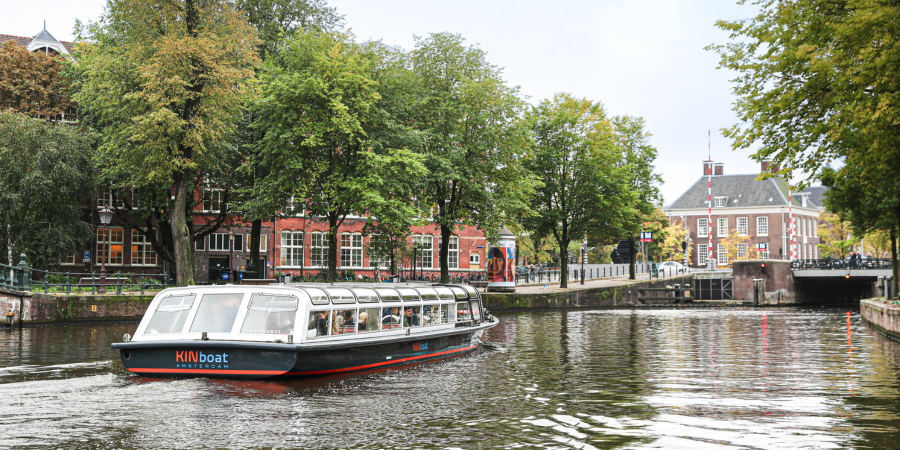 Kinboat covered canal cruise sailing through Amsterdam’s historic canals
