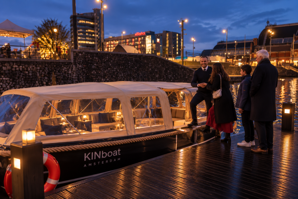 Schipper van KINboat verwelkomt gasten bij de opstapplaats tegenover Amsterdam Centraal voor de Light Festival rondvaart